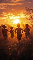 Children running towards a sunset in a grassy field during golden hour photo