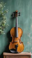 Vintage violin resting against a green wooden wall with decorative foliage photo