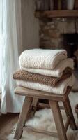 Cozy knitted blankets and dried flowers arranged at a rustic wooden stool in a warm setting photo