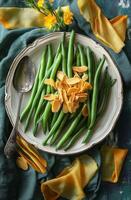 Green beans topped with almond slices on a textured platter surrounded by decorative elements photo