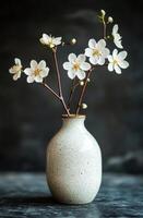 Elegant white blossoms in a simple ceramic vase against a dark background photo