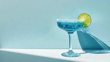 Refreshing cocktail with lime garnish on stylish blue background in bright lighting photo