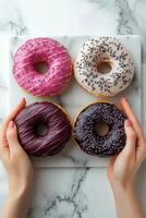 Hands holding three colorful donuts with sprinkles on a marble background photo
