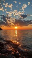 Sunset over the ocean with waves gently lapping against the shore in a tranquil coastal setting photo