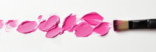 Brush spreads vibrant pink paint across a clean surface for artistic expression photo