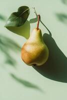 Fresh pear hanging from branch with green leaves on a light green background in morning light photo