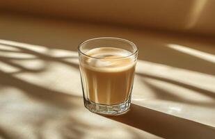 Warm golden beverage resting on a table with soft shadows during afternoon light photo