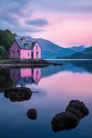 Reflections of a pastel pink house by a tranquil lake with mountains in the background at sunset photo
