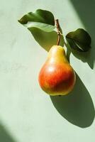 Fresh pear hanging from branch with green leaves on a light green background in morning light photo