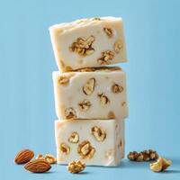 Creamy walnut confection stacked on a blue surface with additional nuts scattered around photo
