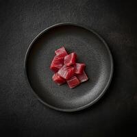 Sashimi preparation featuring fresh tuna cubes on a textured black plate photo