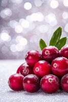 Fresh cranberries dusted with snow on a winter background with soft bokeh lights photo
