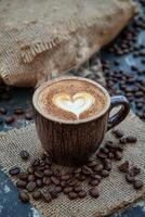 Warm coffee cup with heart latte art and coffee beans on dark background photo
