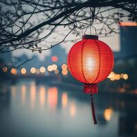 Red lantern illuminating riverside at dusk with city lights in background photo