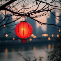 Red lantern illuminating riverside at dusk with city lights in background photo