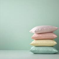Soft pastel pillows stacked against a mint green wall in a minimalist room photo