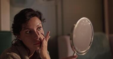 Woman looking at mirror and applying cream video