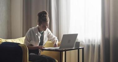 Student taking notes during remote lesson via laptop video