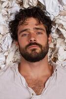 Man with beard lying in crumpled paper photo