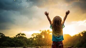 carefree child playing in the rain at sunset photo