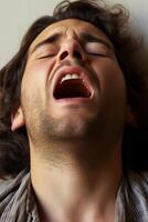 Expressive face of a person with eyes closed and mouth wide open photo