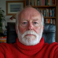 Portrait of a senior man with a white beard wearing a red turtleneck sweater photo