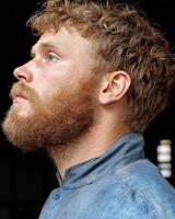 Close up profile of a man with a ginger beard looking up photo