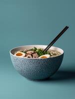 Delicious ramen noodle soup with soft boiled eggs in a speckled bowl photo