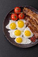 A hearty, delicious breakfast with fried eggs, bacon and tomatoes photo