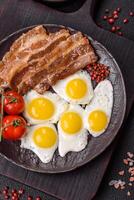 A hearty, delicious breakfast with fried eggs, bacon and tomatoes photo