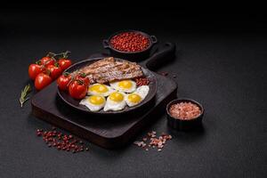 A hearty, delicious breakfast with fried eggs, bacon and tomatoes photo
