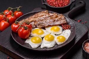 A hearty, delicious breakfast with fried eggs, bacon and tomatoes photo