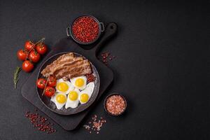 A hearty, delicious breakfast with fried eggs, bacon and tomatoes photo
