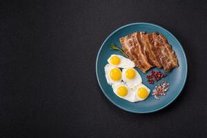 A hearty, delicious breakfast with fried eggs, bacon and tomatoes photo