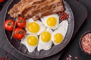 A hearty, delicious breakfast with fried eggs, bacon and tomatoes photo