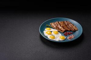 A hearty, delicious breakfast with fried eggs, bacon and tomatoes photo