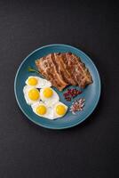 A hearty, delicious breakfast with fried eggs, bacon and tomatoes photo