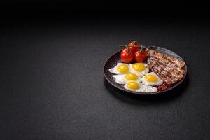 A hearty, delicious breakfast with fried eggs, bacon and tomatoes photo