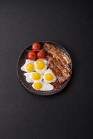 A hearty, delicious breakfast with fried eggs, bacon and tomatoes photo