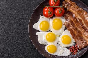 A hearty, delicious breakfast with fried eggs, bacon and tomatoes photo