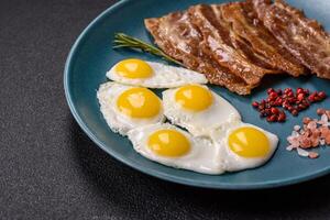 A hearty, delicious breakfast with fried eggs, bacon and tomatoes photo