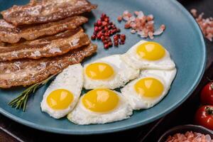 A hearty, delicious breakfast with fried eggs, bacon and tomatoes photo