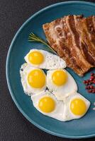 A hearty, delicious breakfast with fried eggs, bacon and tomatoes photo