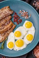 A hearty, delicious breakfast with fried eggs, bacon and tomatoes photo