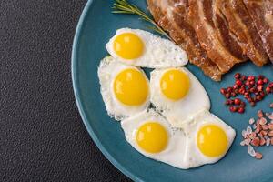 A hearty, delicious breakfast with fried eggs, bacon and tomatoes photo