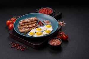 A hearty, delicious breakfast with fried eggs, bacon and tomatoes photo