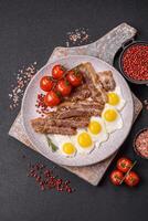 A hearty, delicious breakfast with fried eggs, bacon and tomatoes photo