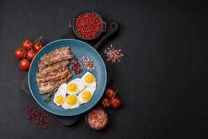 A hearty, delicious breakfast with fried eggs, bacon and tomatoes photo