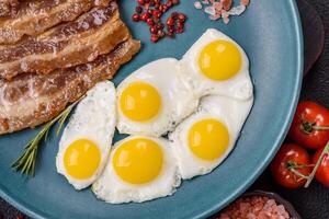 A hearty, delicious breakfast with fried eggs, bacon and tomatoes photo