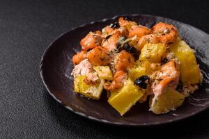 Baked salmon pieces with potatoes, cheese and olives photo